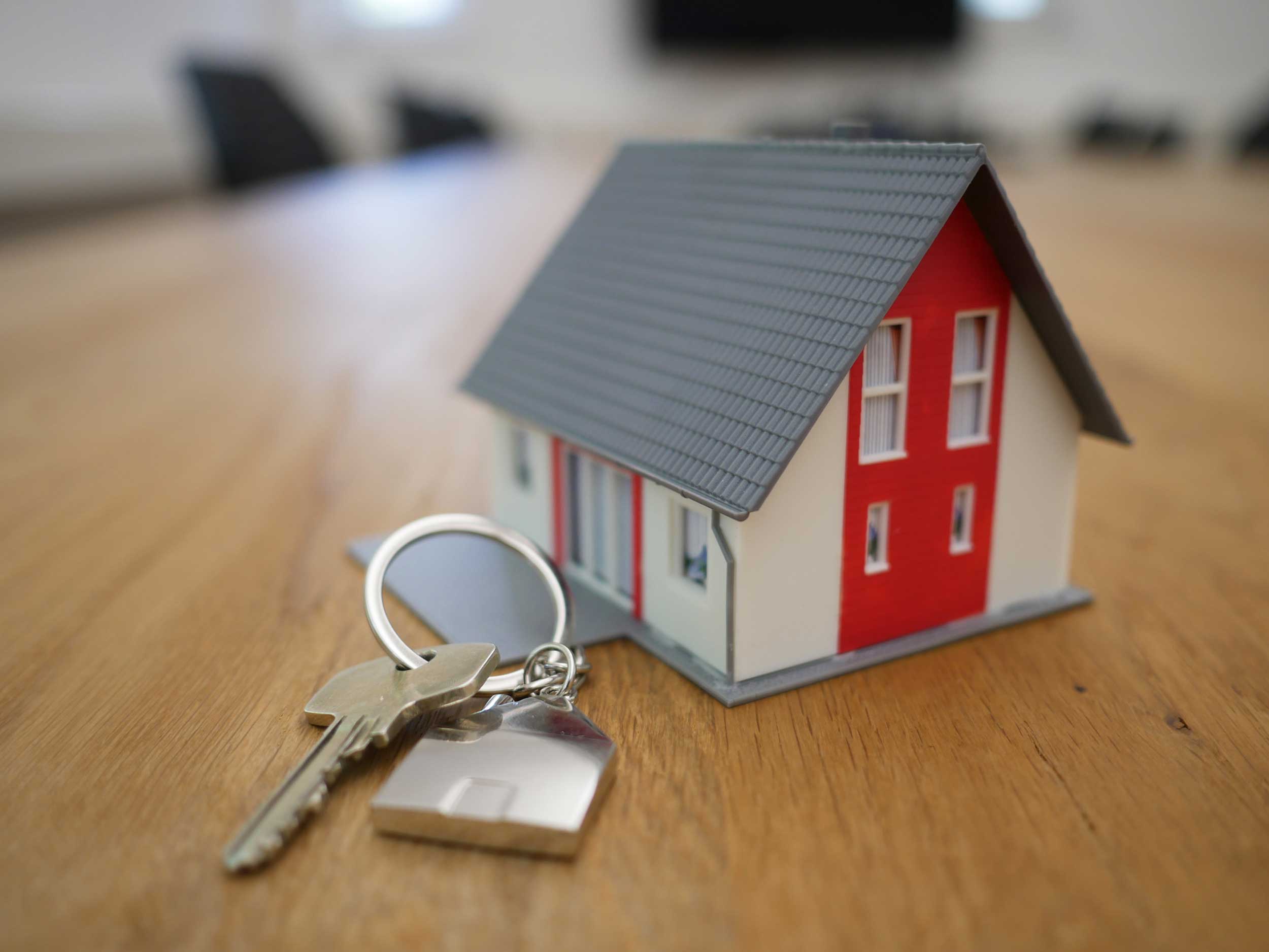 Model home resting on a table with a set of keys laying beside the home depicting Mortgage Protection Insurance importance.